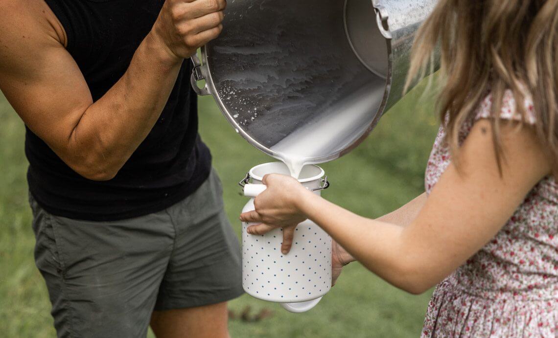 zwei Personen beim Milch umfüllen – Symbolbild